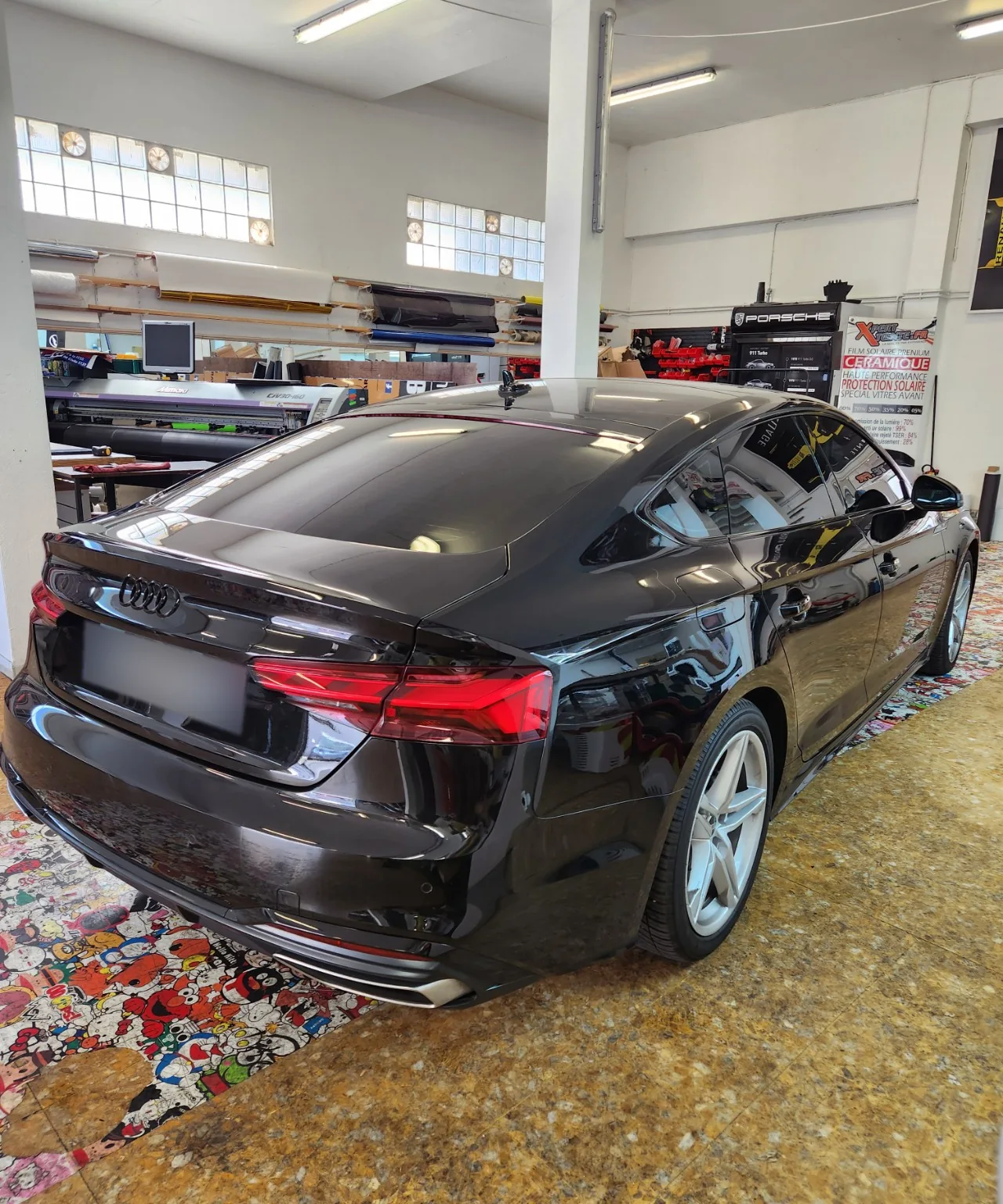 Audi A5 Sportback – trois-quarts arrière à 95 % Audi A5 Sportback noire vue de trois-quarts arrière droit, avec la lunette et les vitres arrière teintées à 95 %.