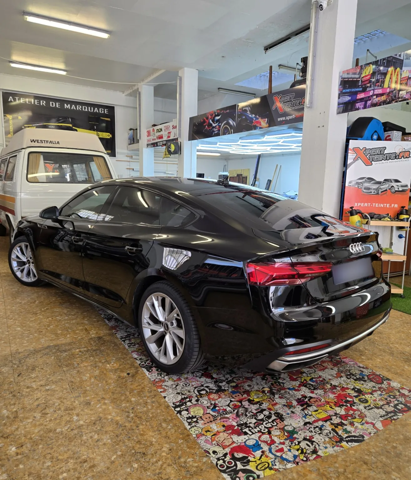 Audi A5 Sportback B9 – vue arrière gauche Vue arrière gauche de l’Audi A5 Sportback B9 noire, après la pose de films solaires chez Xpert Teinte à Toulon.