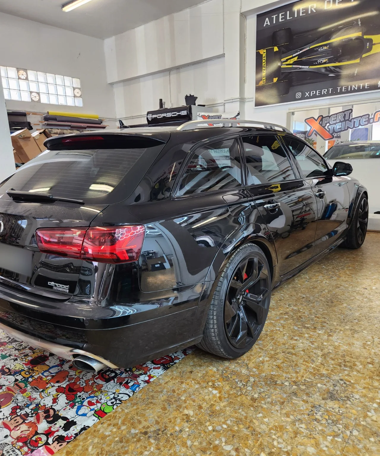 Audi A6 Avant – piano black et vitres teintées 50 % / 65 % Vue arrière droite de l’Audi A6 Avant noire après déchromage des contours de vitres en piano black.