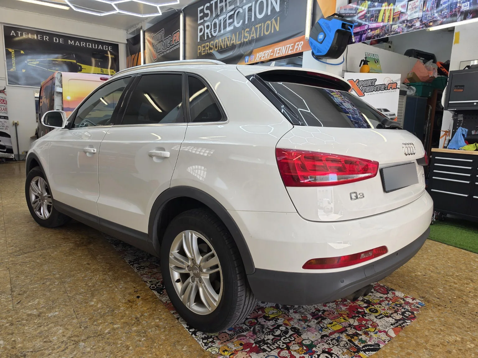Audi Q3 – film solaire à 80 % sur le trois-quarts arrière Audi Q3 blanc vu de trois quarts arrière gauche, avec les vitres arrière et la lunette teintées.