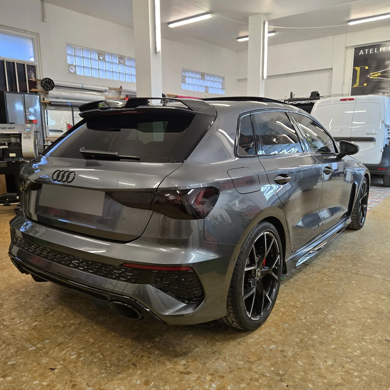 Audi RS3 – trois-quarts arrière full black à 95 % Audi RS3 Sportback grise vue de trois quarts arrière avec les vitrages et feux teintés.