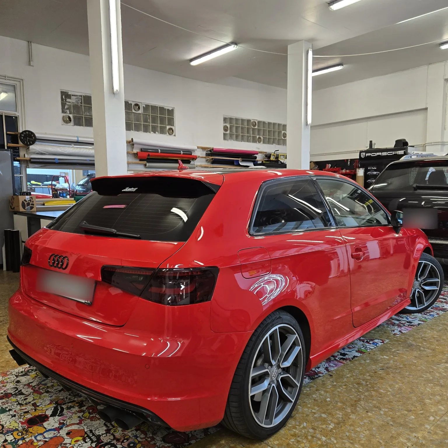 Audi S3 rouge 3 portes – vue arrière droite Vue arrière droite de l’Audi S3 rouge trois portes avec ses vitres arrière à 80 % et ses feux fumés.