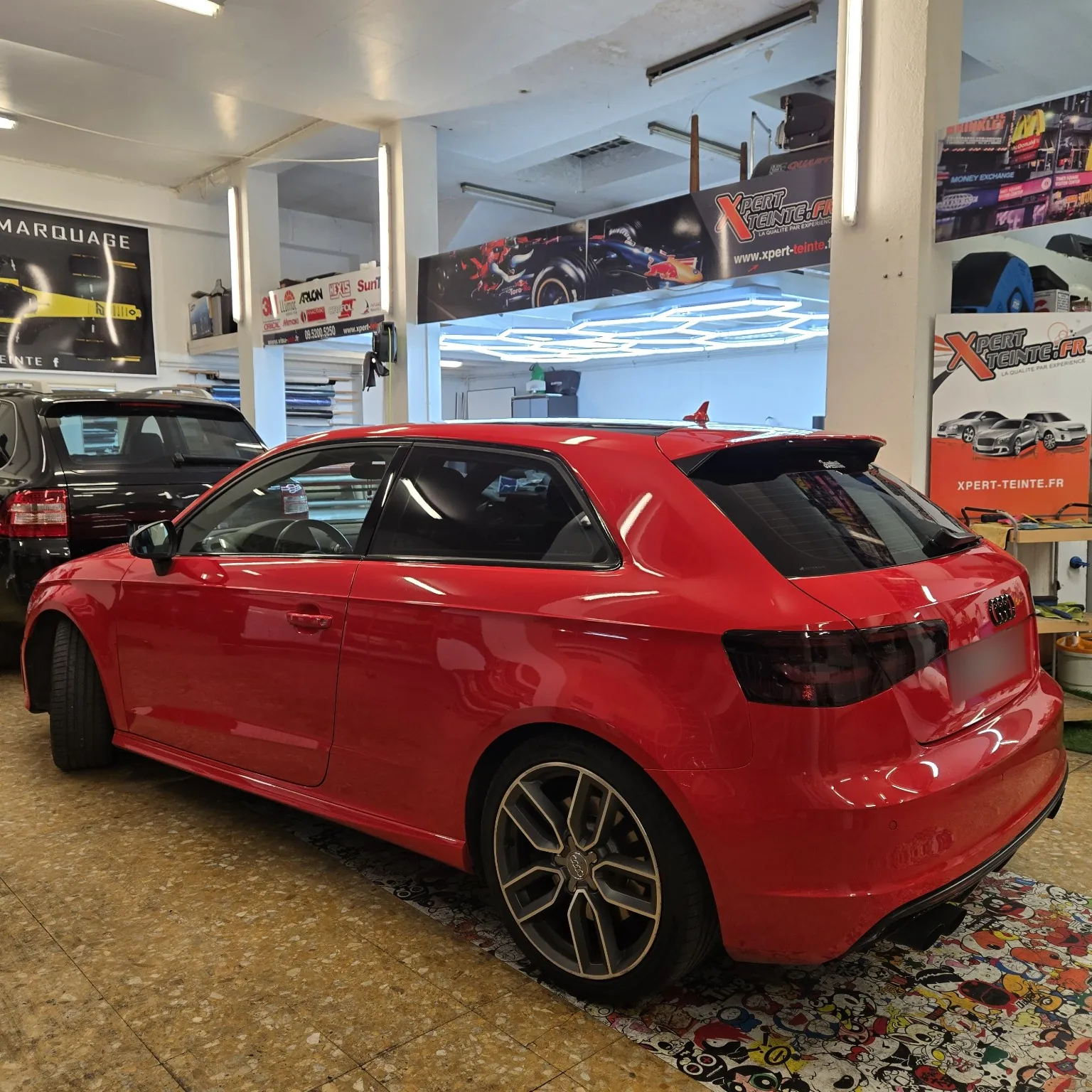 Audi S3 rouge 3 portes – vue arrière gauche Audi S3 rouge trois portes, vitres avant à 15 %, arrière à 80 % et feux teintés, vue arrière gauche à Toulon.