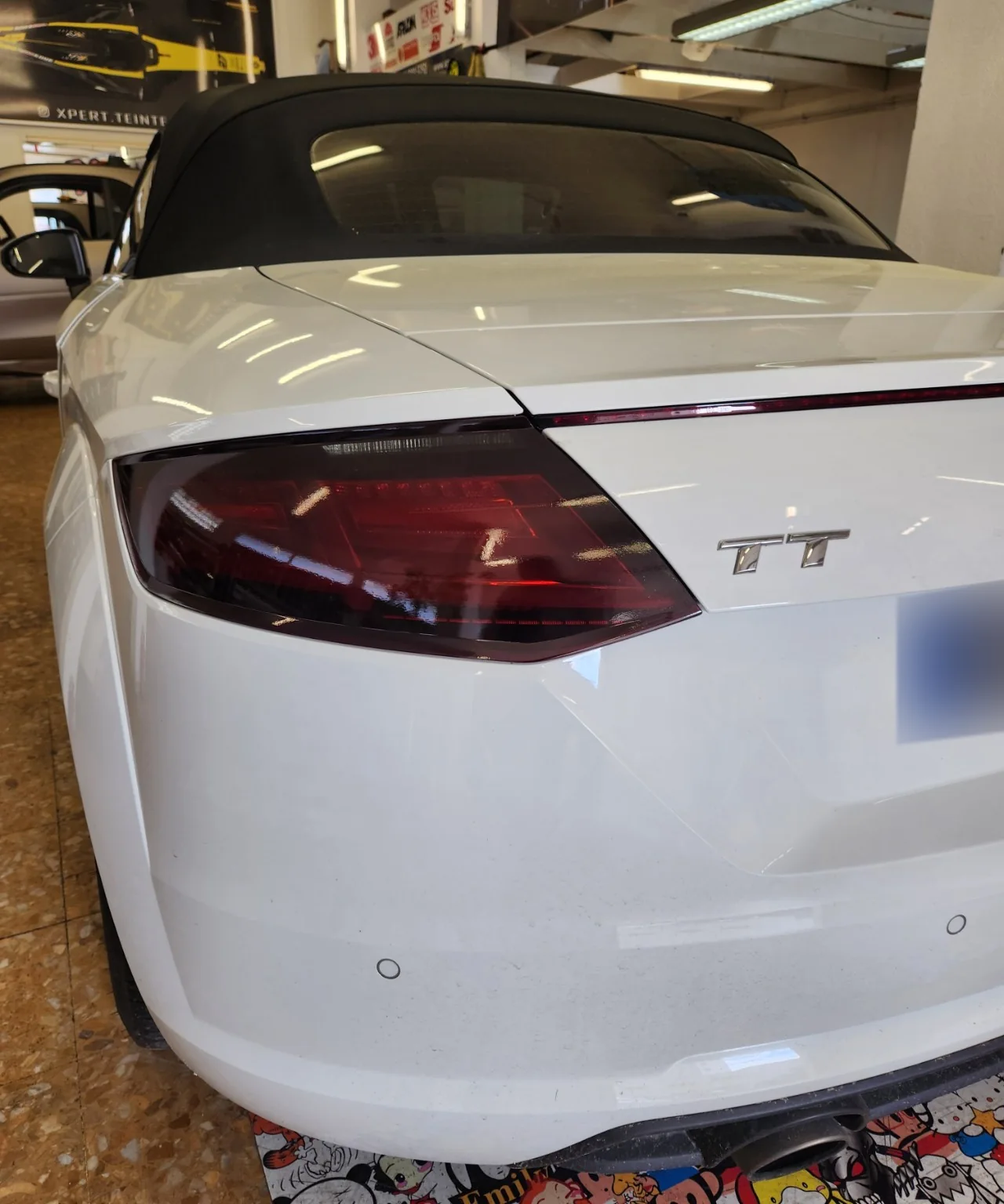 Audi TT cabriolet – lunette arrière teintée à 80 % Vue rapprochée de l’arrière de l’Audi TT Roadster blanche, avec sa lunette intégrée à la capote noire.