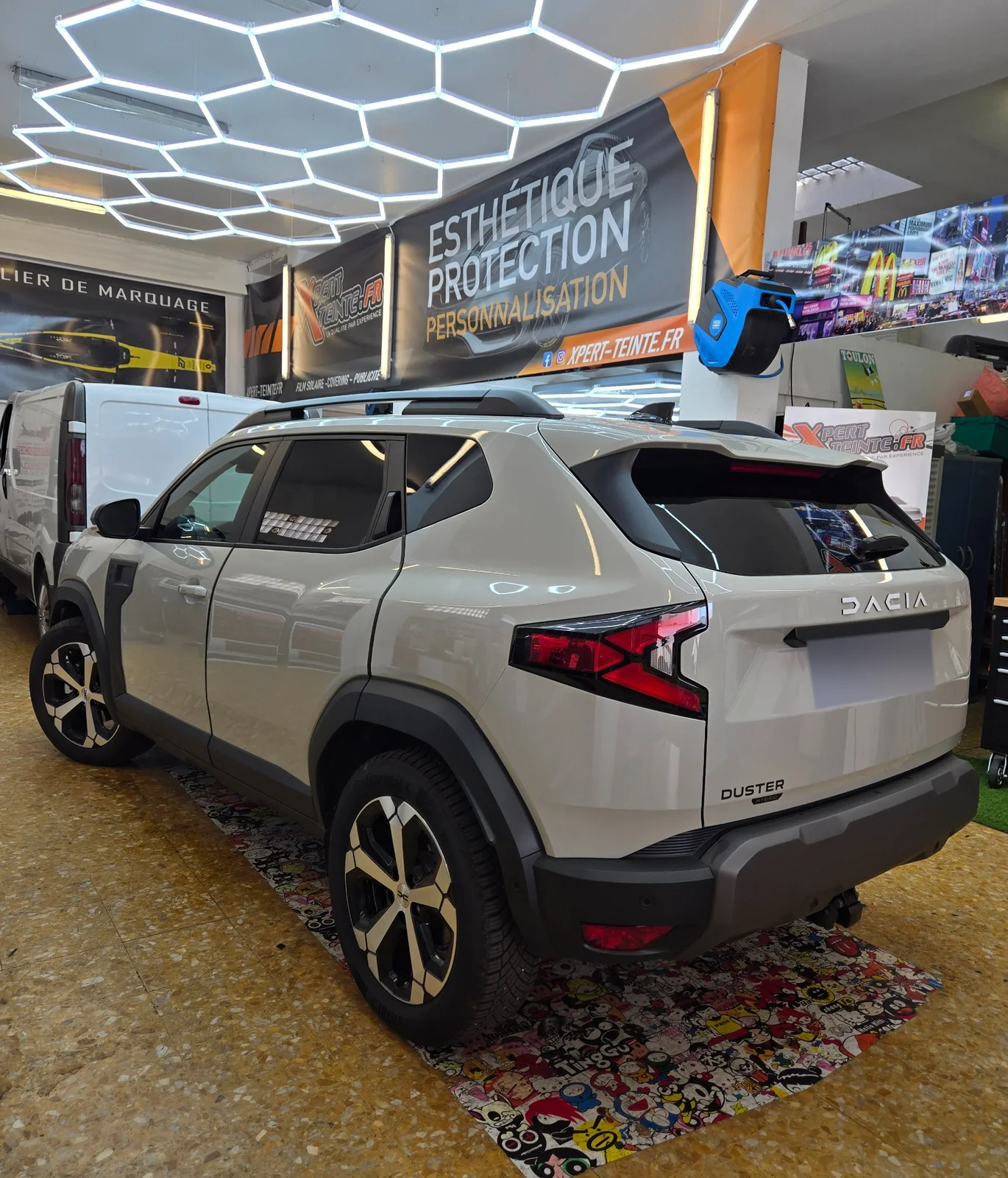 Dacia Duster – vitrages teintés et vue arrière Dacia Duster beige avec badge Hybrid et vitrages arrière sombres, vu de trois quarts arrière.