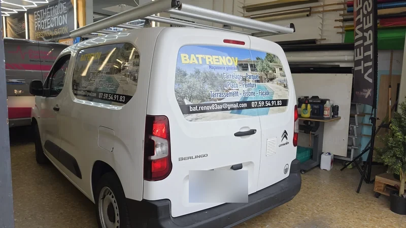 Panneaux publicitaires BAT’RENOV sur les portes arrière et le côté d’un Citroën Berlingo blanc