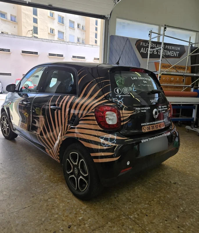 Décor publicitaire bronze et noir sur une Smart, vue arrière trois quarts
