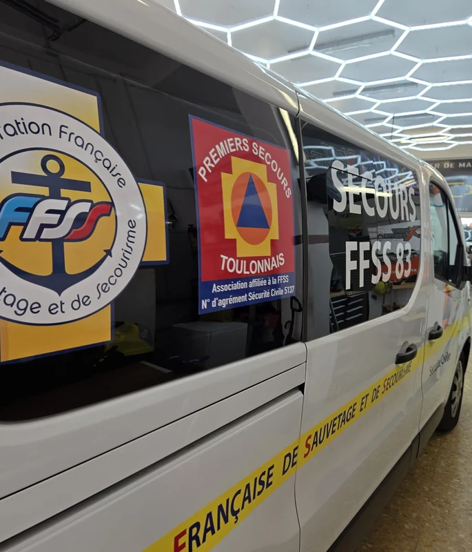 Détail des logos FFSS 83 et Premiers Secours Toulonnais sur un véhicule blanc
