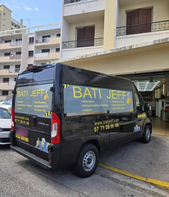 Grand lettrage jaune BATI JEFF sur les panneaux d’un fourgon noir de rénovation