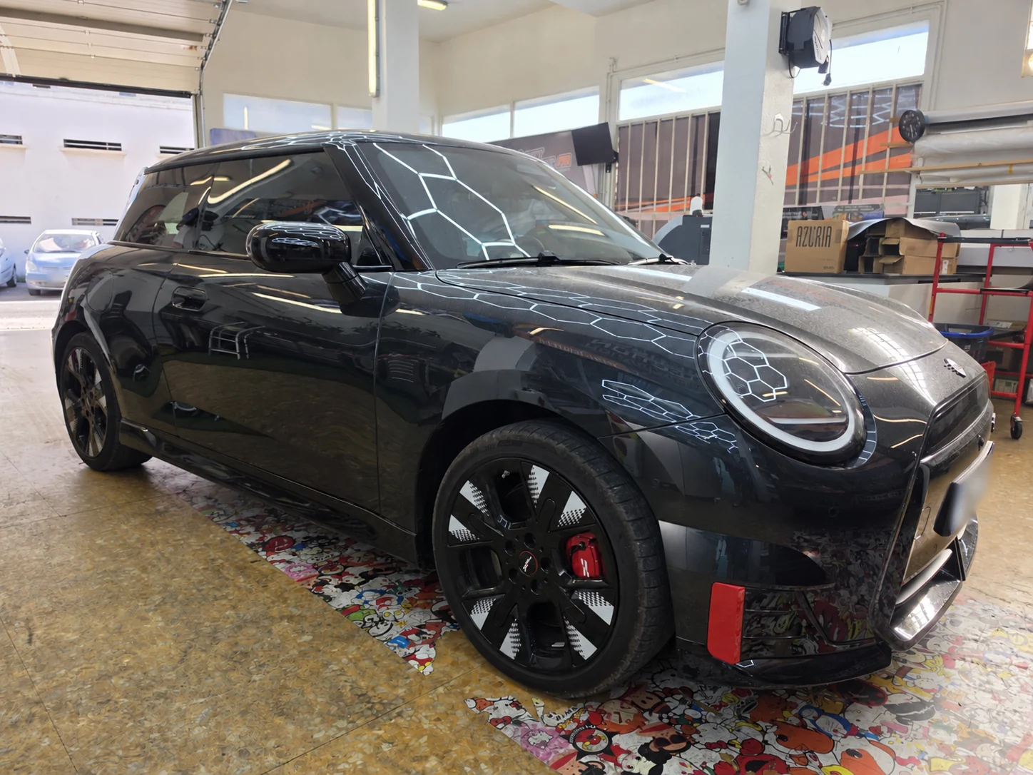 Vitres teintées MINI Cooper électrique à Toulon – vue avant MINI Cooper électrique trois portes gris foncé, vue de trois quarts avant droit dans l’atelier Xpert Teinte à Toulon.