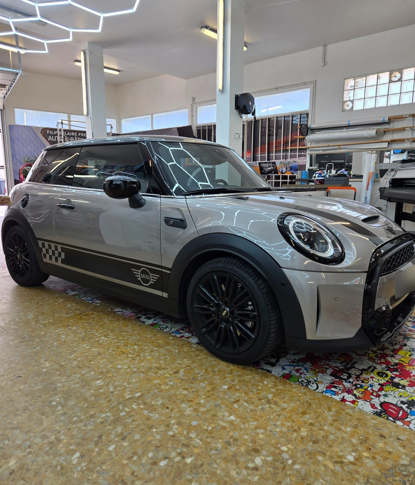 MINI Cooper S – film solaire et décoration latérale à Toulon MINI Cooper S vue de côté et de trois quarts avant, avec vitrages teintés et bandes latérales noires à damier.