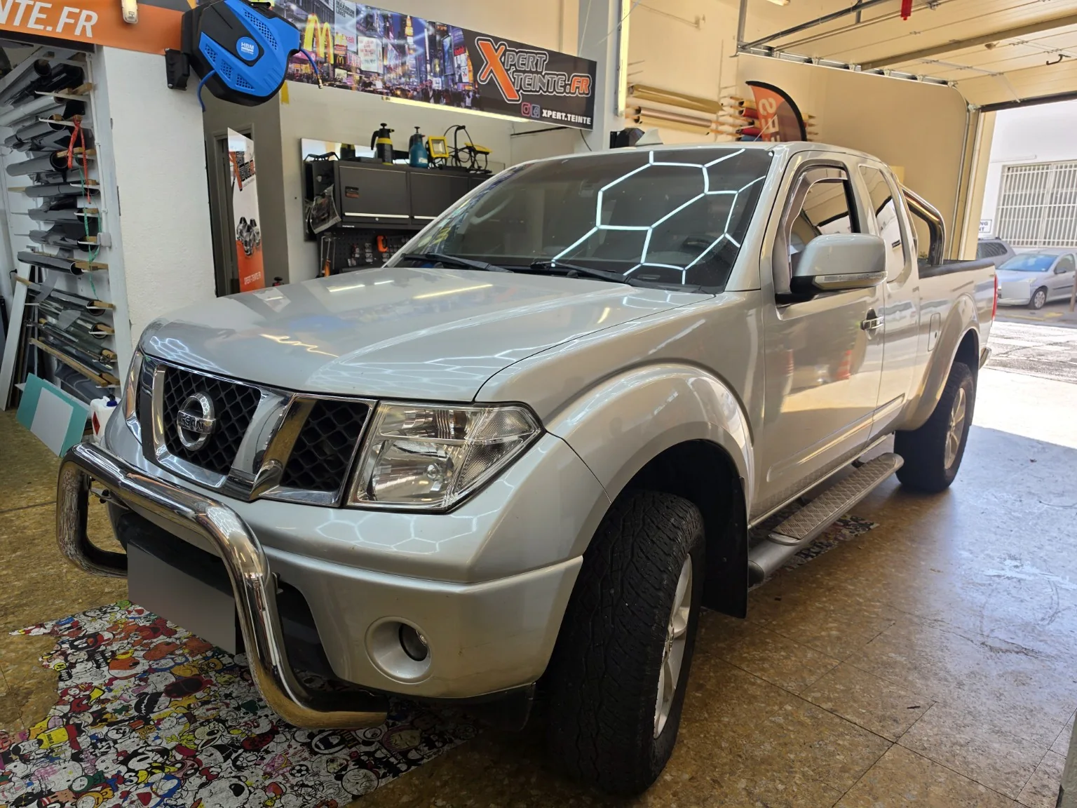 Vitres teintées Nissan Navara D40 à Toulon – vue avant Nissan Navara D40 King Cab argenté vu de trois quarts avant, avec ses vitres teintées dans l’atelier Xpert Teinte à Toulon.
