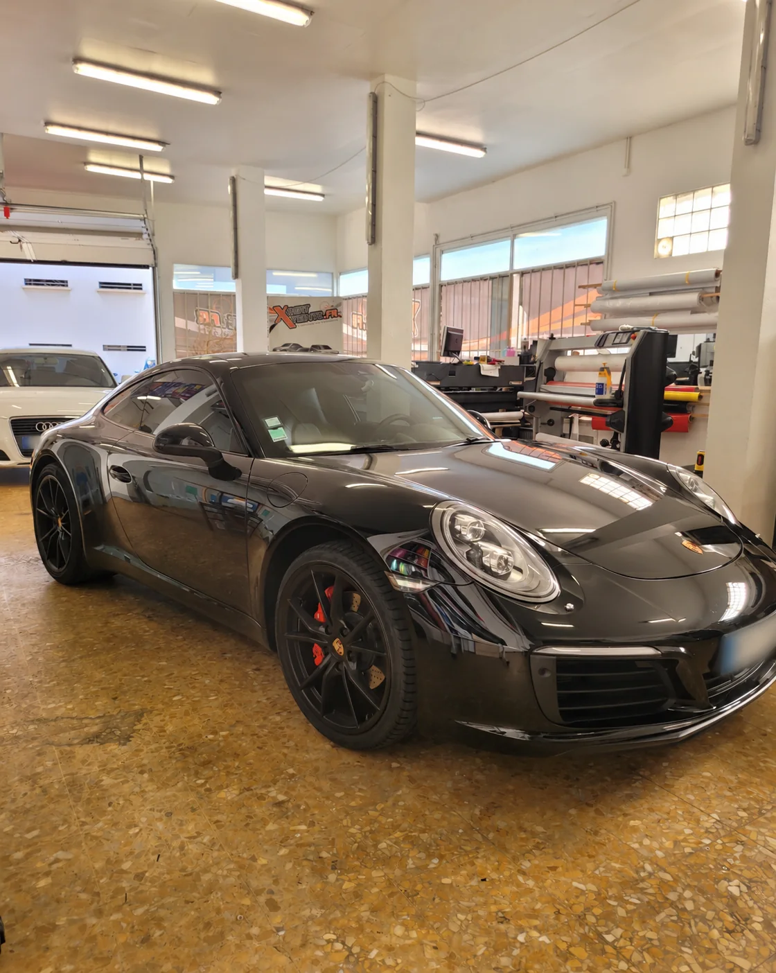 Vitres teintées Porsche 911 à Toulon – Carrera noire Vitres teintées Porsche 911 : vue avant de la Carrera noire dans l’atelier Xpert Teinte à Toulon.