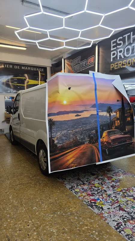 Positionnement d’un décor imprimé de coucher de soleil sur les portes arrière d’un fourgon blanc