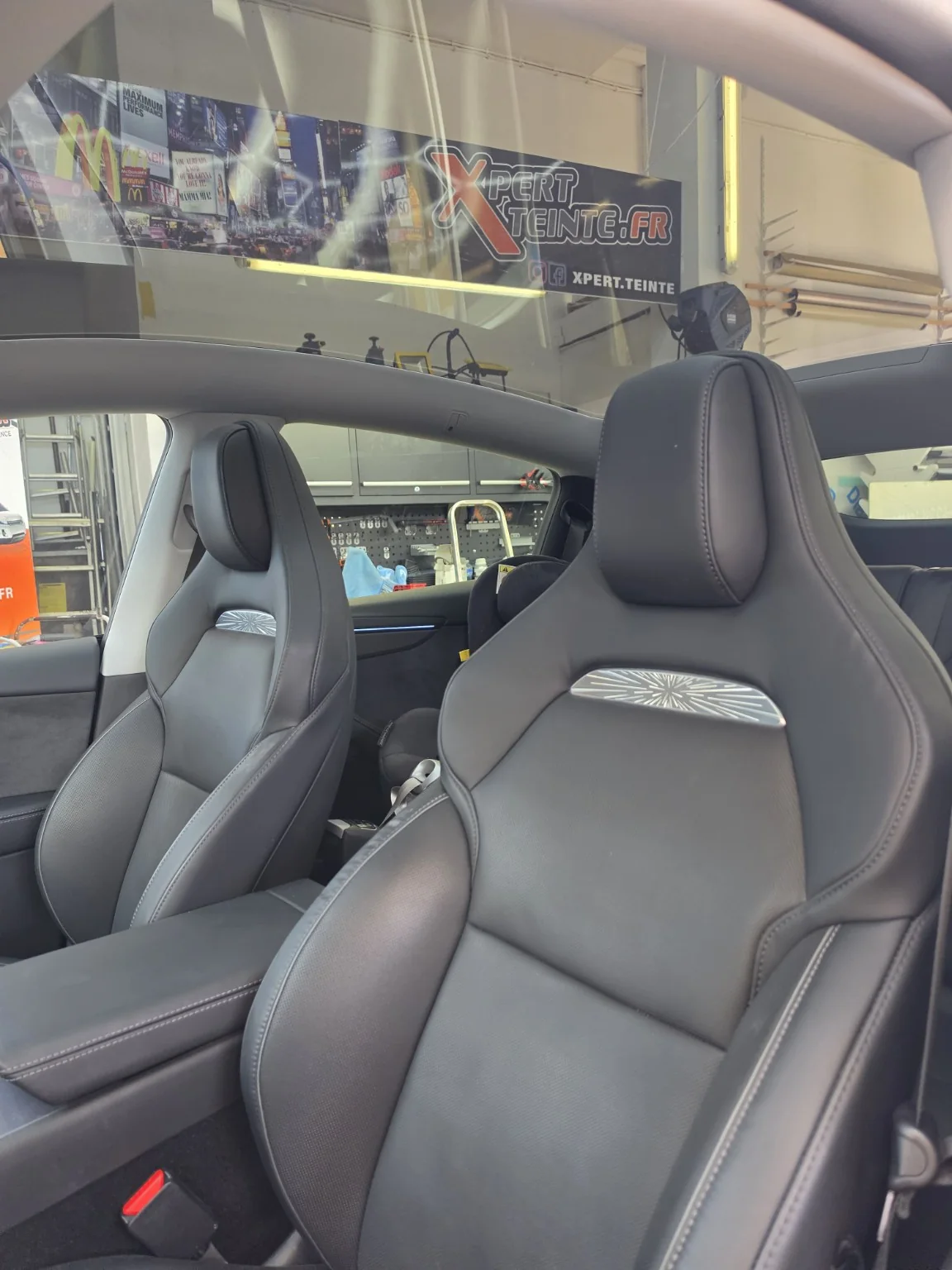 Film solaire pour toit panoramique Tesla Model Y – Toulon Intérieur de la Tesla Model Y montrant les sièges avant et le pavillon panoramique en verre traité avec un film solaire.