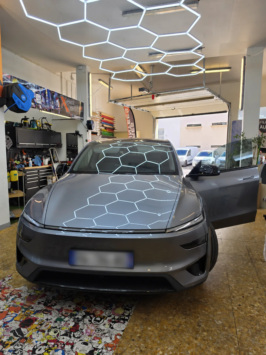 Film solaire Tesla Model Y à Toulon – vitre avant Tesla Model Y vue de face avec la porte conducteur ouverte et la vitre avant relevée dans l’atelier de Toulon.