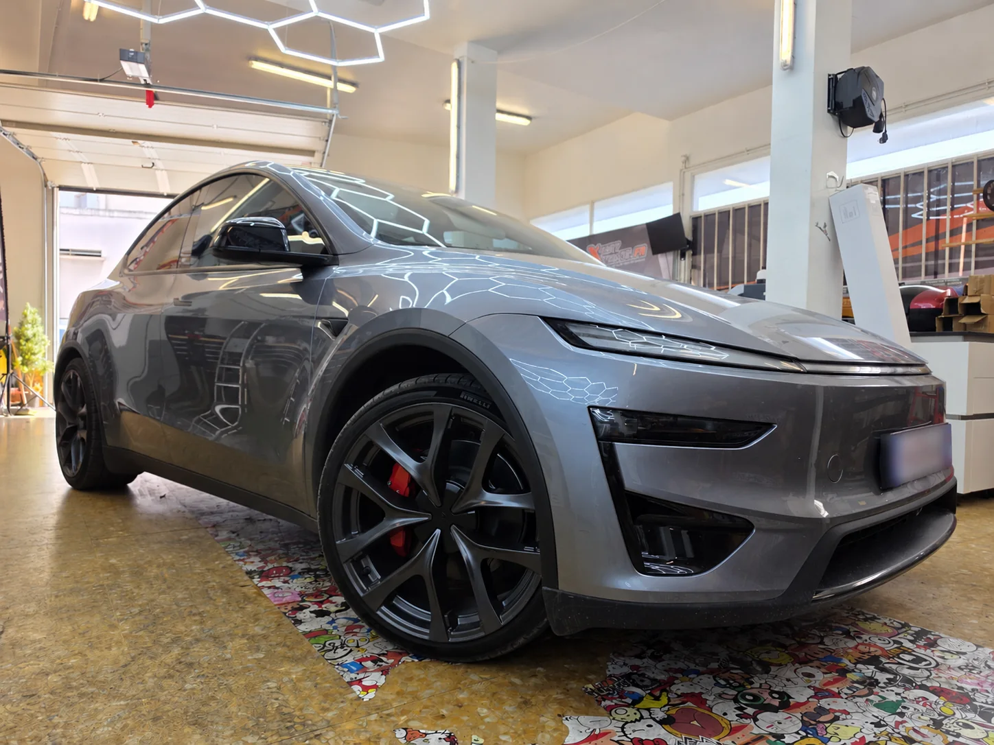 Protection solaire Tesla Model Y à Toulon – vue extérieure Tesla Model Y grise photographiée de trois quarts avant en vue basse, avec ses vitres latérales teintées et ses jantes noires.