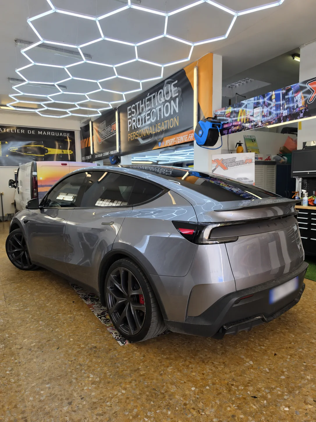 Vitres teintées Tesla Model Y à Toulon – vue arrière Tesla Model Y grise vue de trois quarts arrière, avec ses vitrages teintés dans l’atelier Xpert Teinte à Toulon.