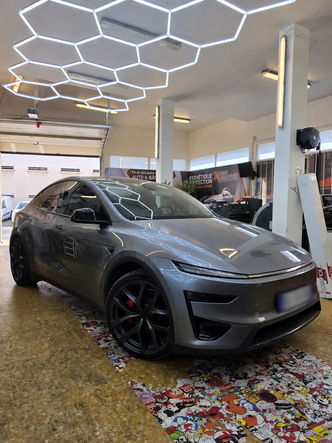 Vitres teintées Tesla Model Y à Toulon – vue avant Vitres teintées Tesla Model Y : vue avant de la voiture grise dans l’atelier Xpert Teinte à Toulon.