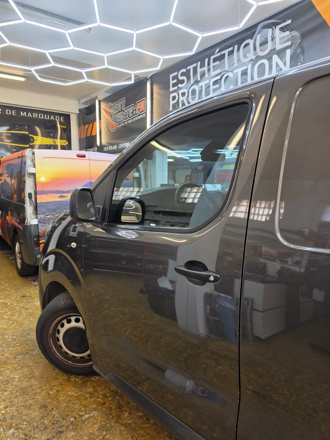 Toyota Proace – film solaire sur la vitre avant à 50 % Détail de la vitre latérale avant teintée, du rétroviseur et de la porte du Toyota Proace gris.