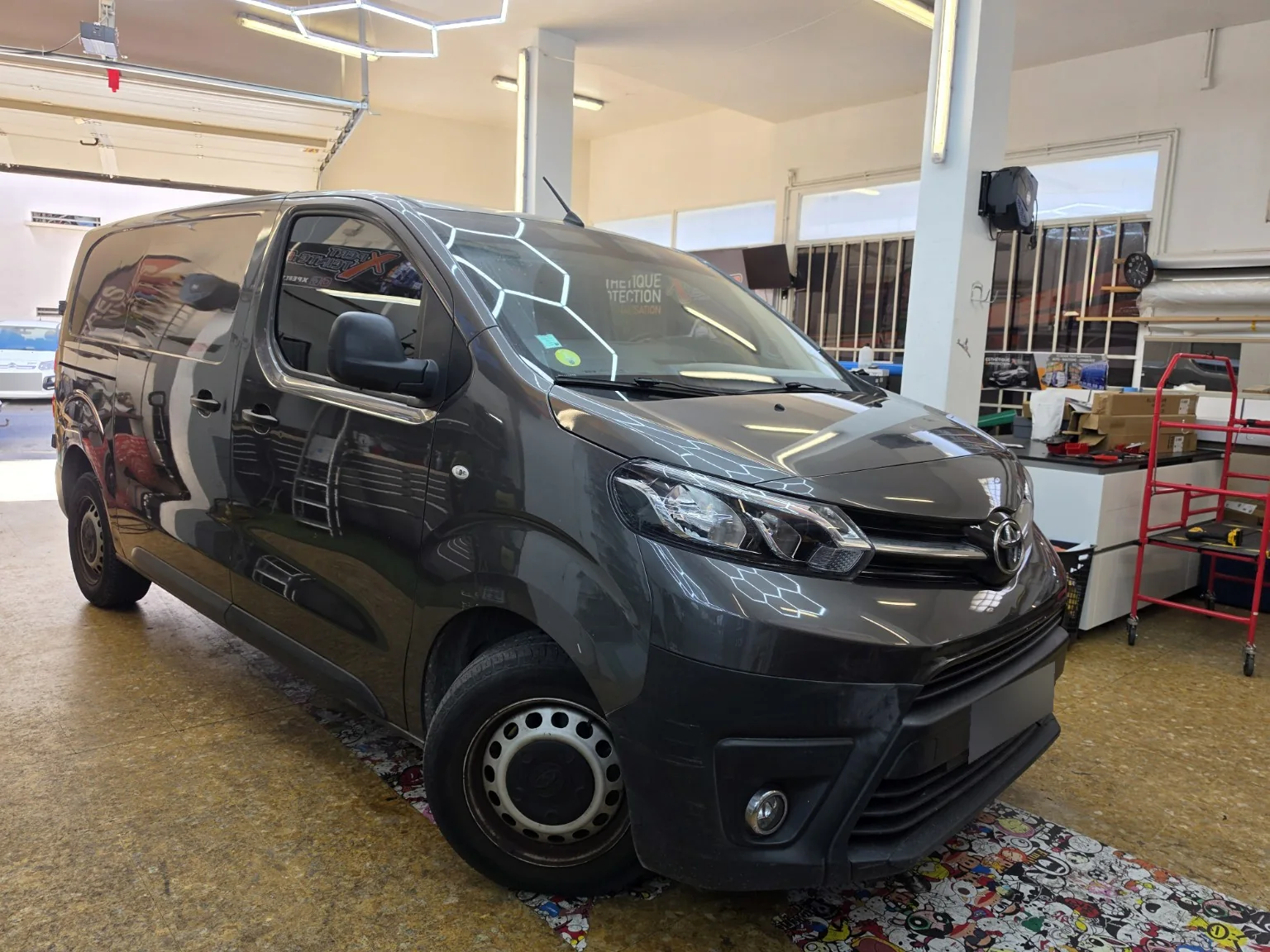 Vitres teintées Toyota Proace à Toulon – vue avant Toyota Proace gris vu de trois quarts avant, avec ses vitres latérales teintées et son bandeau pare-soleil.