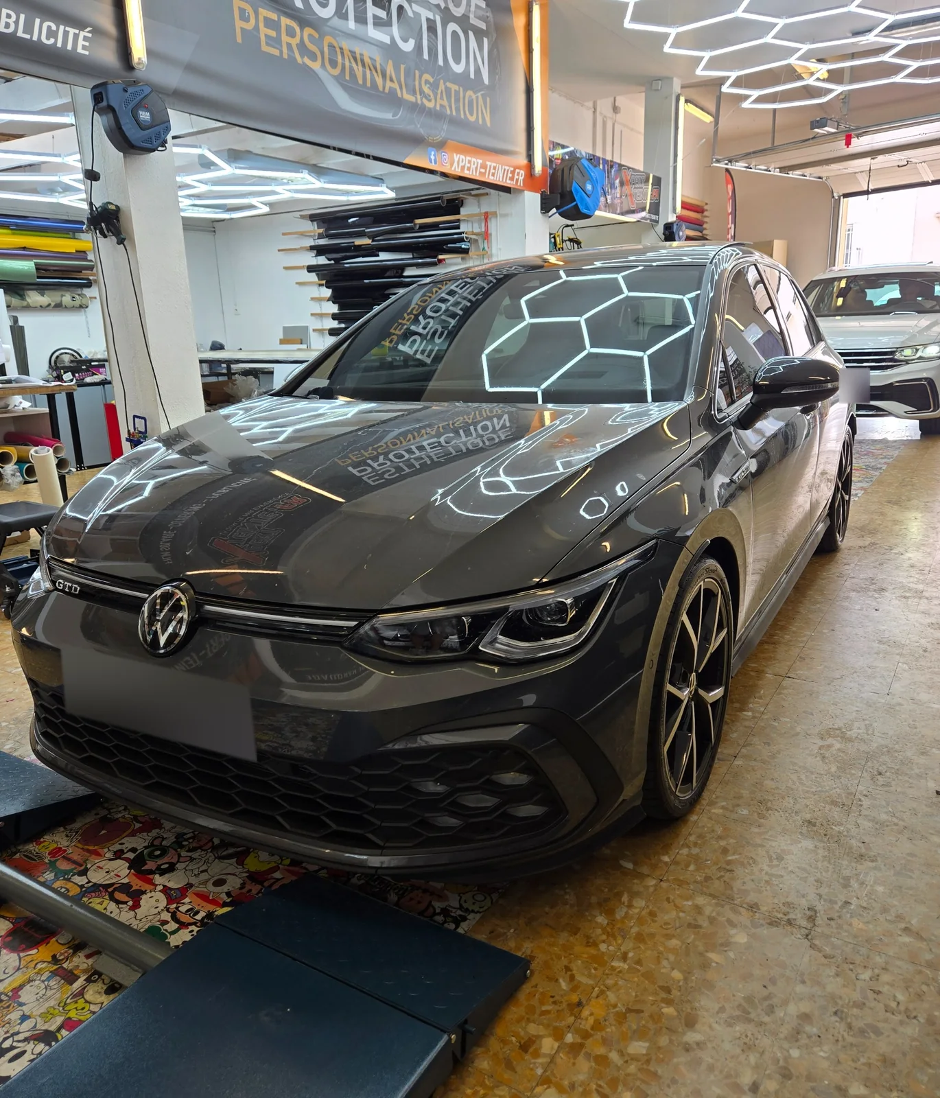 Volkswagen Golf 8 GTD – films solaires à Toulon Volkswagen Golf 8 GTD gris foncé, pare-brise et vitres latérales visibles dans l’atelier.