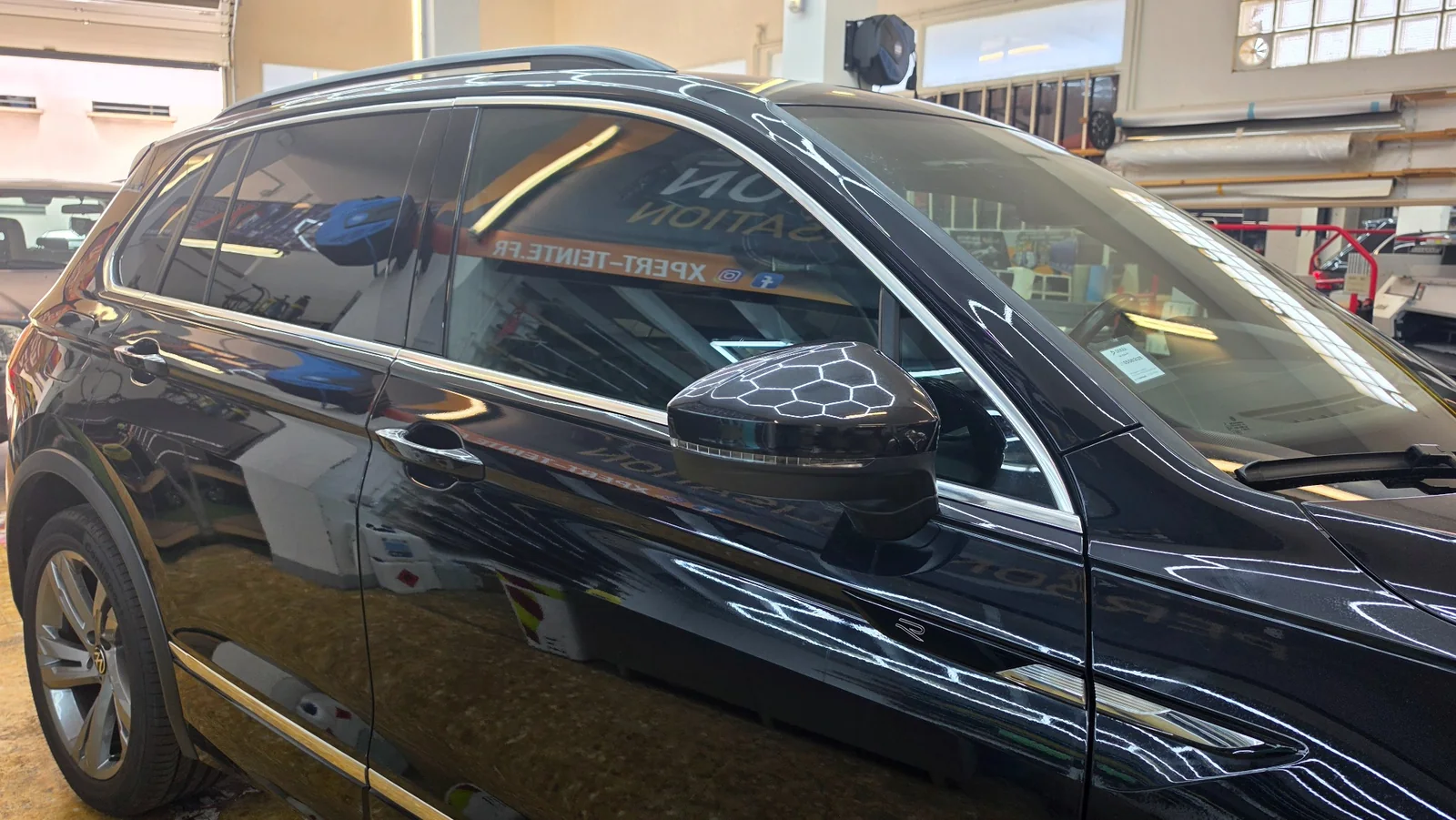 Film solaire Volkswagen Tiguan à Toulon – vitre avant Détail de la vitre avant droite et du rétroviseur du Volkswagen Tiguan noir dans l’atelier.