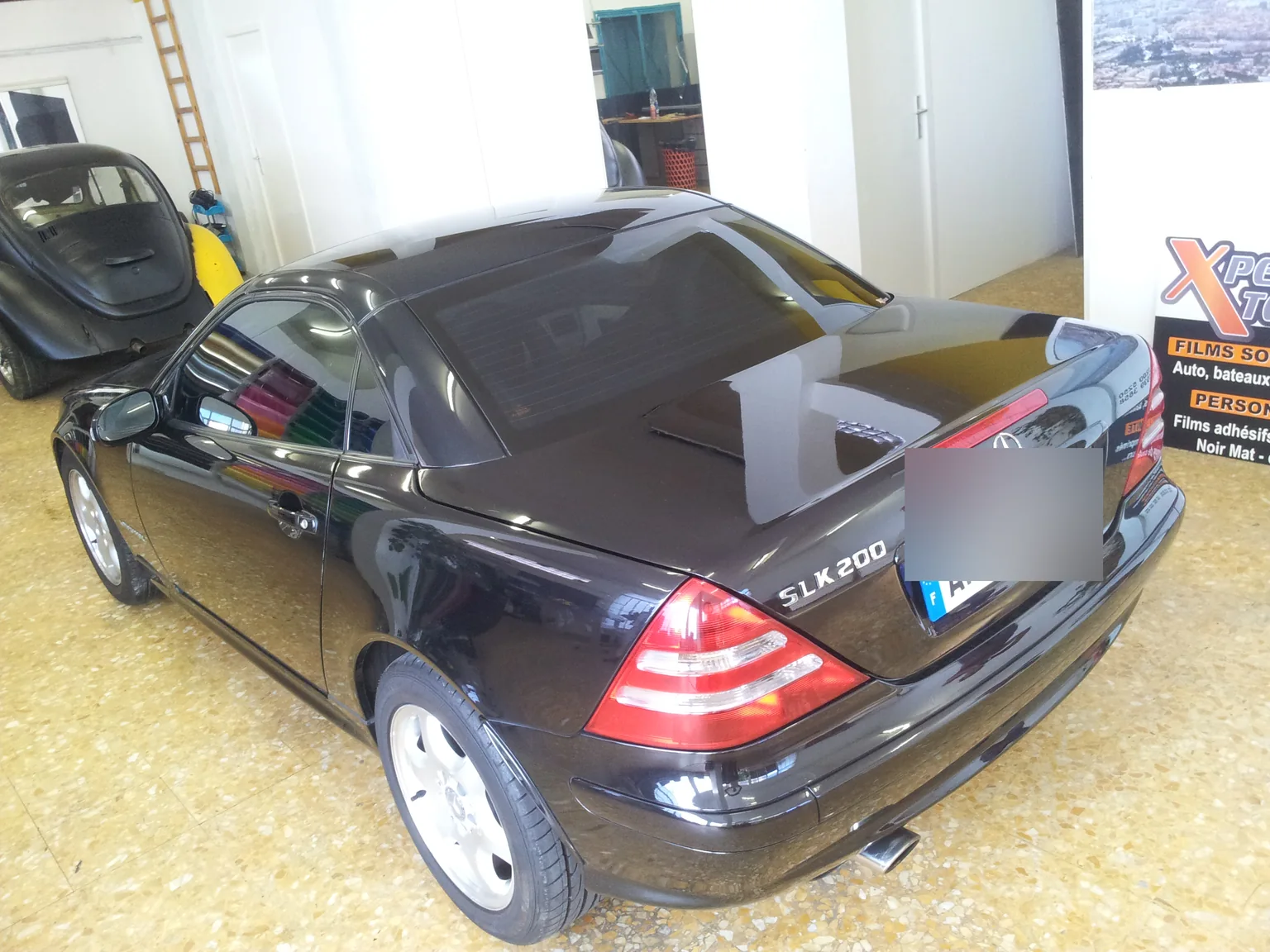 Mercedes SLK 200 noire, toit rigide fermé et lunette arrière à l’atelier. Mercedes SLK 200 noire, toit rigide fermé et lunette arrière à l’atelier — Xpert Teinte à Toulon.