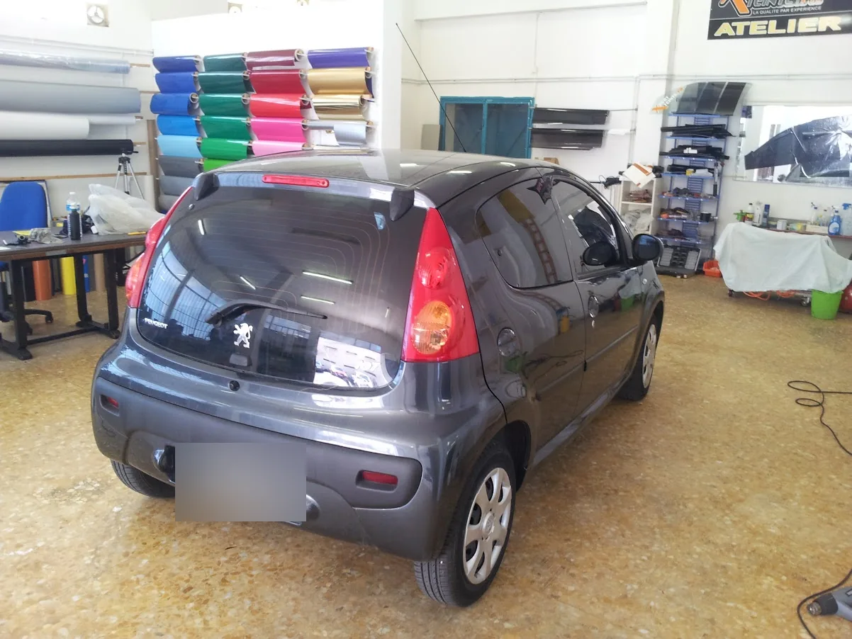 Peugeot 107 noire : vue arrière et vitres latérales à l’atelier. Peugeot 107 noire : vue arrière et vitres latérales à l’atelier — Xpert Teinte à Toulon.